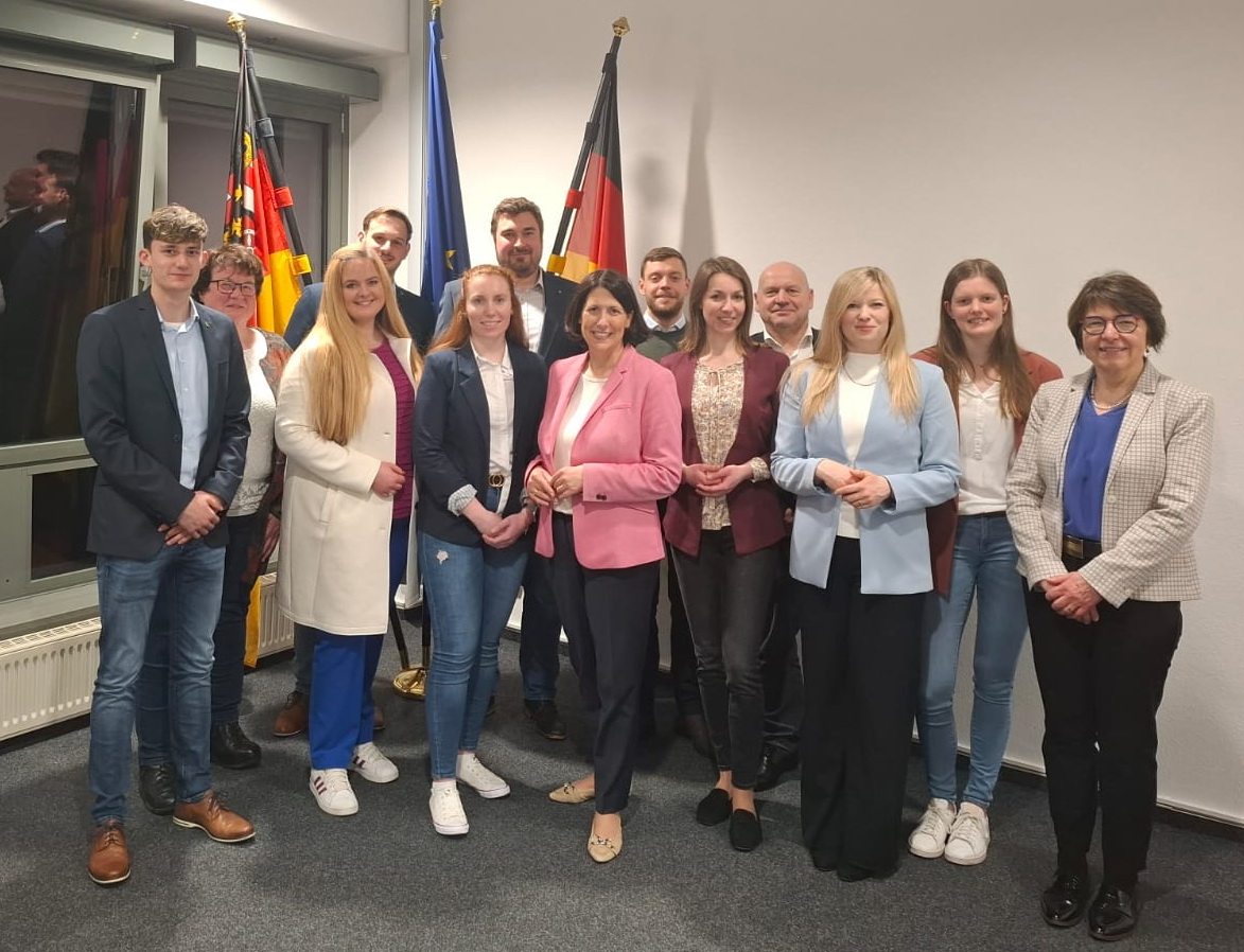 Mehrere Vertreter der Landjugendverbände Rheinland-Nassau und RheinhessenPfalz stehen gemeinsam mit Ministerin Daniela Schmitt vor Flaggen mit Rheinland-Pfalz-Emblem