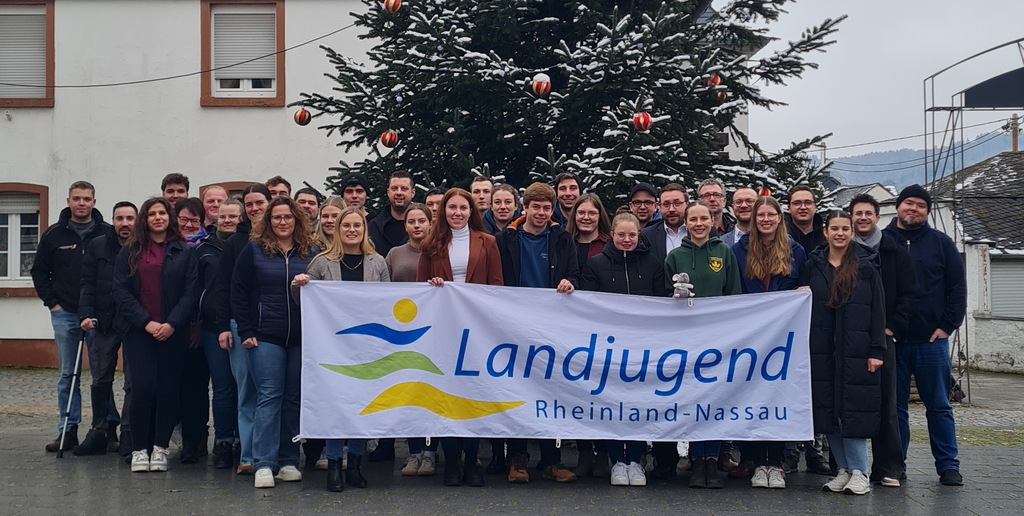 Gruppenbild der Delegierten und des Hauptamts vor winterlicher Kulisse in Mehring. Die Gruppe hält ein Banner der Landjugend.
